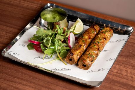 Two grilled rosemary seekh kebabs served with green chutney and side salad at Kanishka.